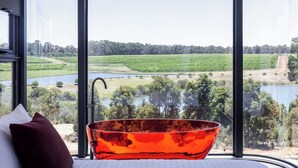 A room with a large window offering a view of a lake, fields, and trees. - Aravina Escapes (Yallingup)
