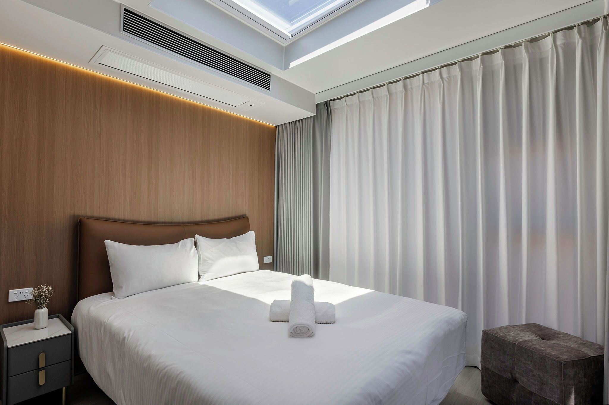 Una habitación de hotel moderna con una cama grande, tragaluz y vistas al exterior.