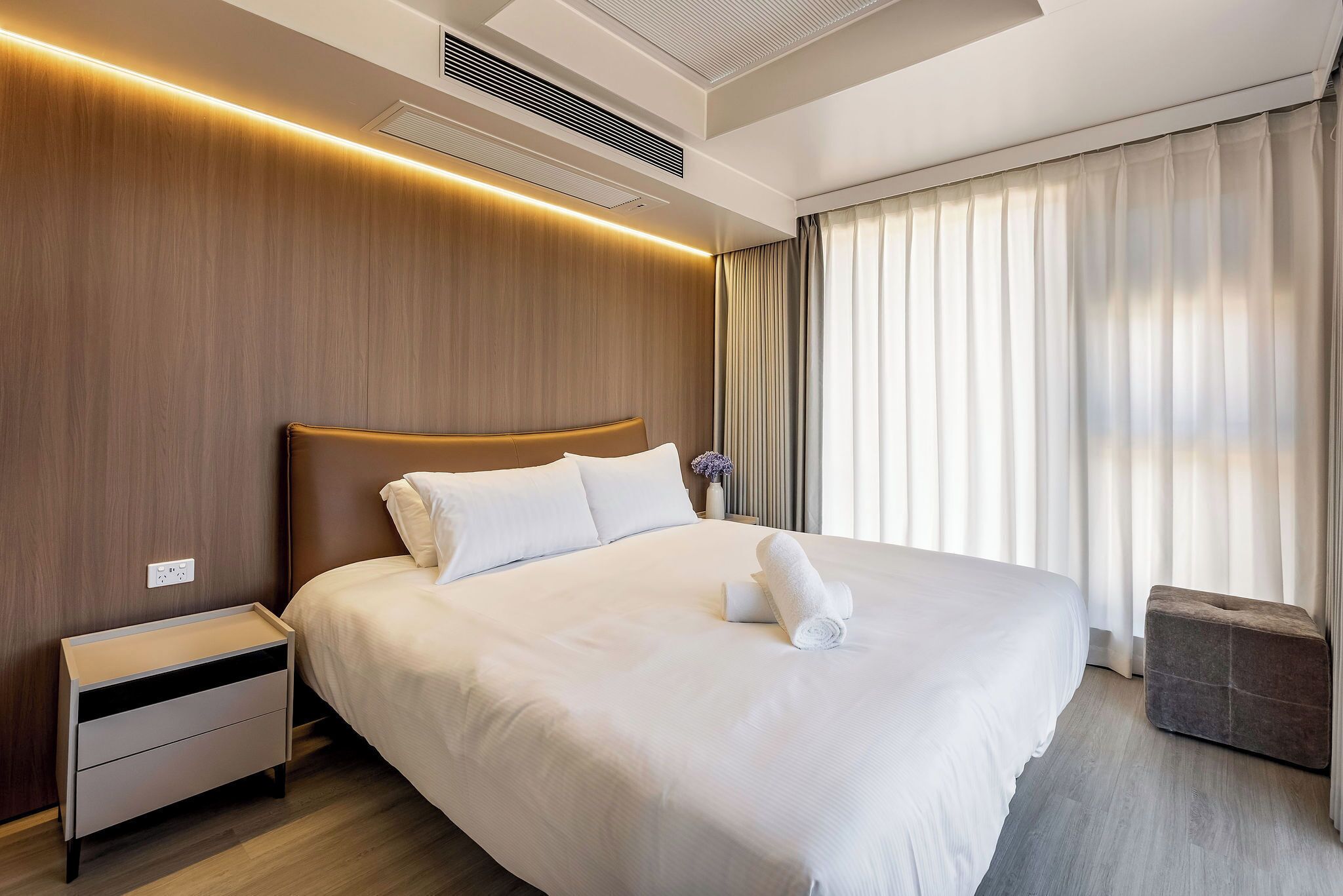 Una habitación de hotel moderna con una cama grande, una mesita de noche y un pequeño rincón de descanso.