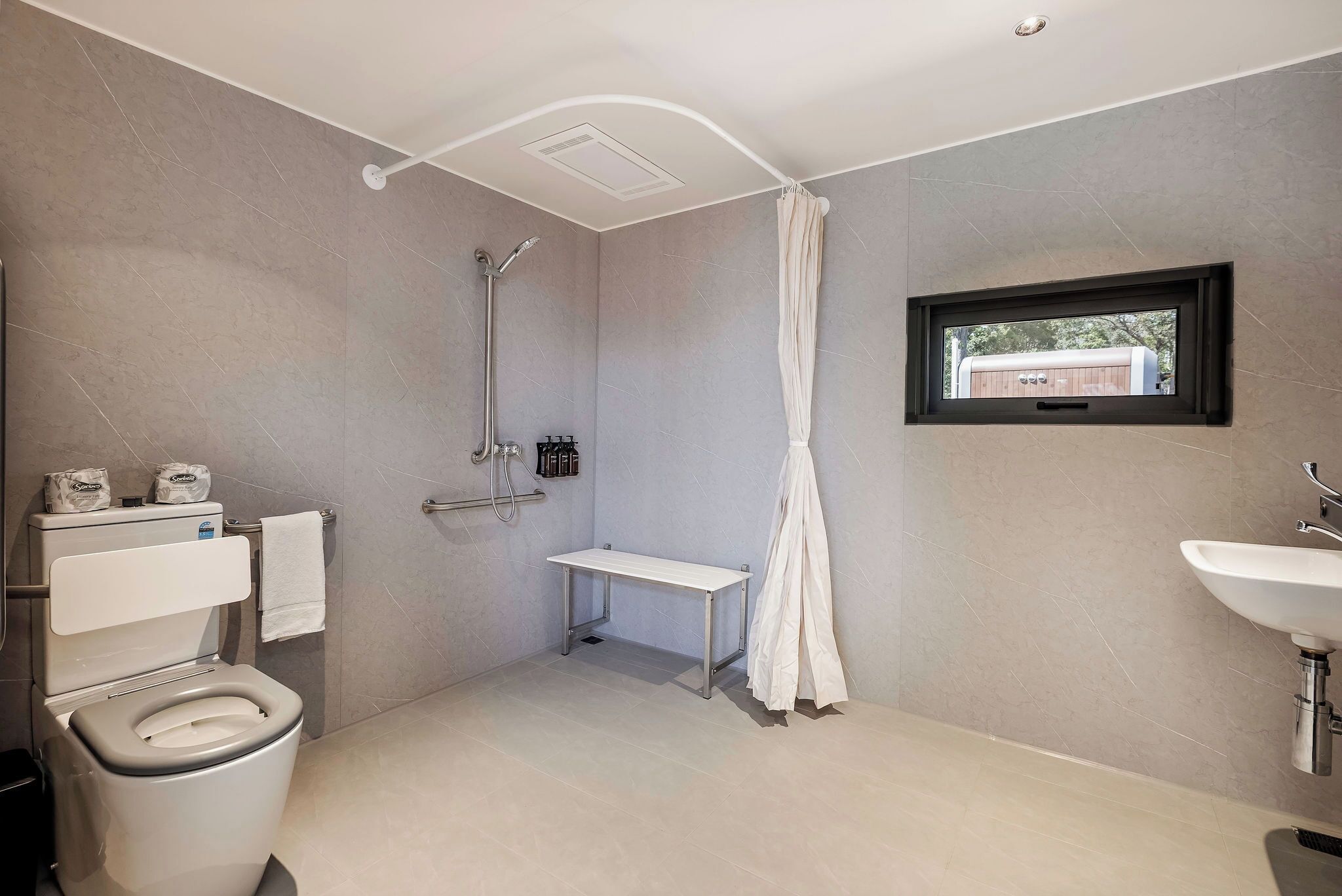 A modern bathroom with a shower, toilet, and sink.