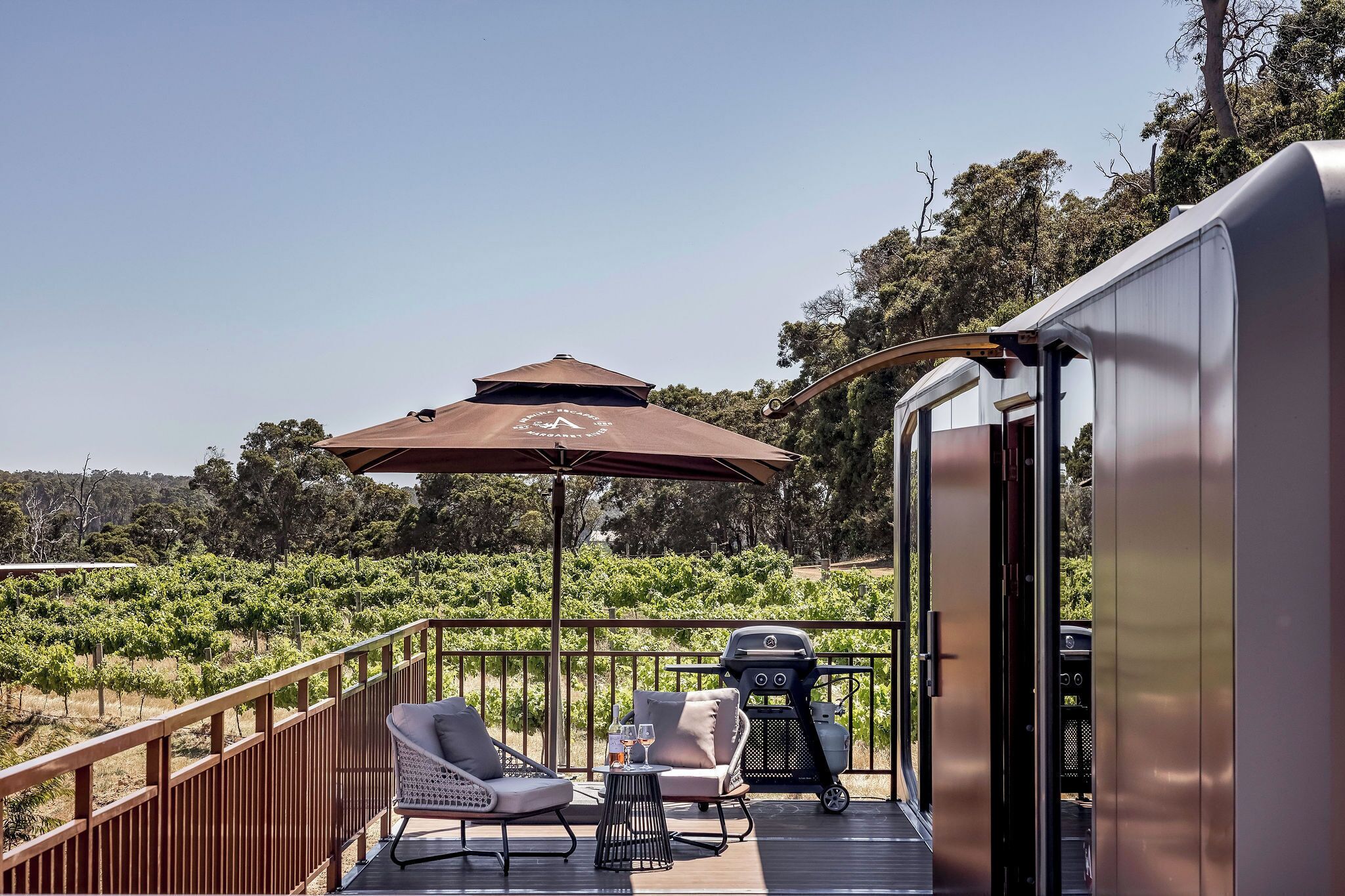 A deck with outdoor seating, a grill, and a view of a vineyard.