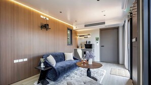 A modern living room with a sofa, a coffee table, and a small side table. There is a kitchen area visible in the background. - Aravina Escapes (Yallingup)