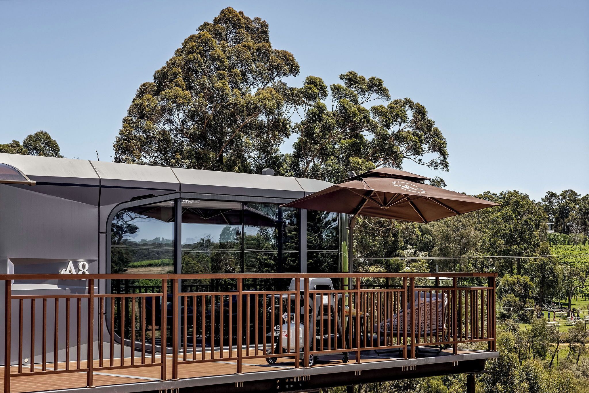A modern building with a glass facade, a wooden deck, and a metal railing.