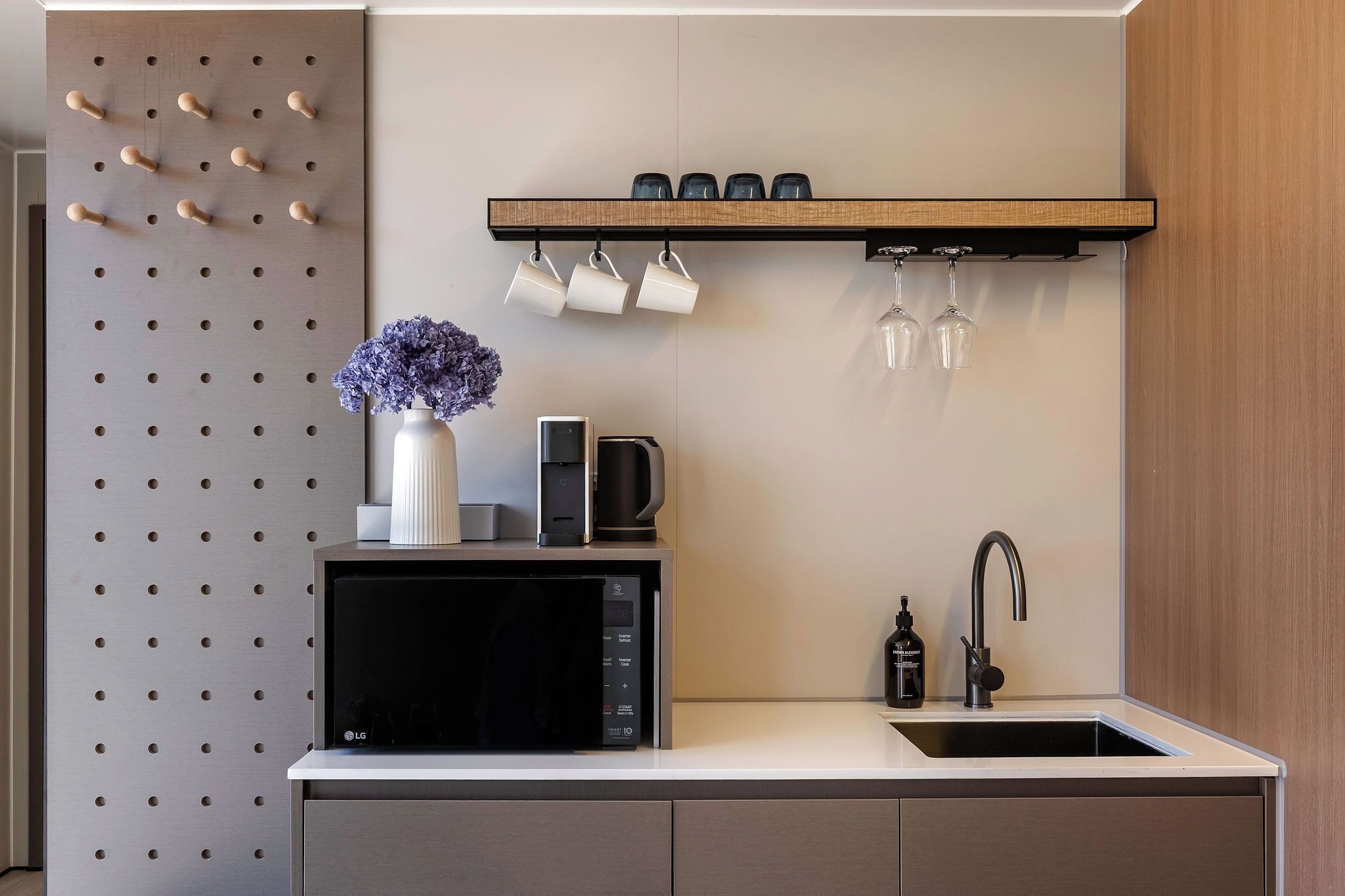 A modern kitchen with a built-in microwave, a coffee maker, and a sink with a faucet.
