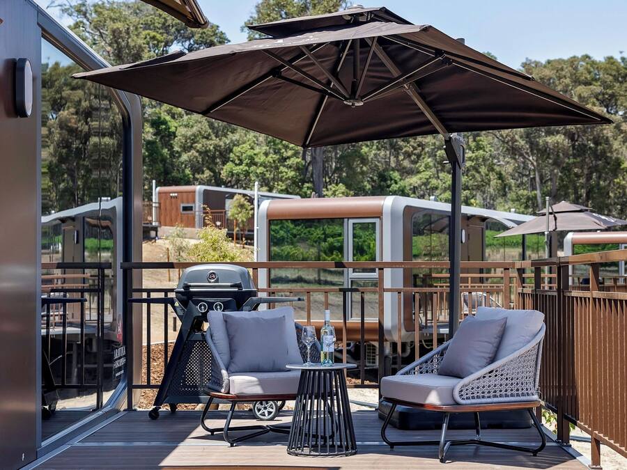 A deck with outdoor furniture, a grill, and a large umbrella.