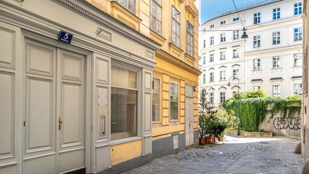 A narrow cobblestone street flanked by historic buildings with large windows and a sign indicating the number 5. - Blueground | Innere Stadt, w/d, nr St. Stephen's Cathedral (Vienna)