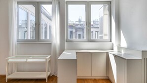 A bright, modern room with large windows, a white desk, and a small white table. - Blueground | Innere Stadt, w/d, nr St. Stephen's Cathedral (Vienna)
