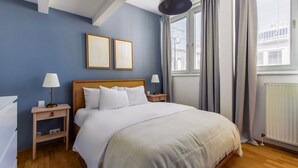 A bedroom with a bed, two bedside tables, a lamp, a window with curtains, and two framed pictures on the wall. - Blueground | Innere Stadt, w/d, nr St. Stephen's Cathedral (Vienna)