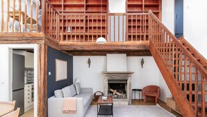 A loft-style living area with a fireplace, wooden staircase, and a dining area. - Blueground | Innere Stadt, w/d, nr St. Stephen's Cathedral (Vienna)
