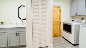 Una cocina con mostrador blanco, puerta de madera y lavadora.