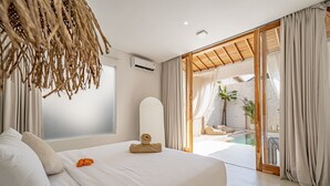 A bedroom with a large bed, a view of a pool, and a sliding glass door leading to an outdoor area. - Villa Estrella Seseh (Munggu)