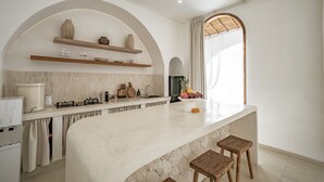 A modern kitchen with a marble countertop, wooden stools, and a built-in island. - Villa Estrella Seseh (Munggu)