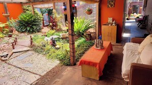 A cozy room with a wooden bench, a small table with a red cloth, and a bed. - Wellbeing Courtyard Beachside Retreat (Port Noarlunga South)