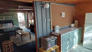 A compact living space with a kitchenette, a bed, and a dining area. - Wellbeing Courtyard Beachside Retreat (Port Noarlunga South)
