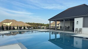 Une piscine dotée de chaises longues et d’un espace de repos couvert, le tout entouré de maisons.