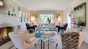 A spacious living room with a fireplace, comfortable seating, and a view of the outdoors. - Riviera Gem - Designer decorated private 2BR home (Santa Barbara)