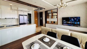 Una cucina moderna con frigorifero integrato, un'area pranzo con tavolo apparecchiato per due e una TV fissata alla parete.