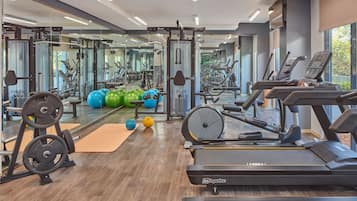 A gym with cardio equipment, weightlifting stations, and exercise balls.