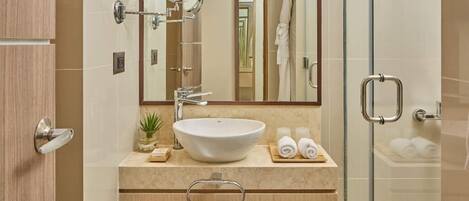 Un baño moderno con un espejo grande, un lavabo y una cabina de ducha de vidrio.