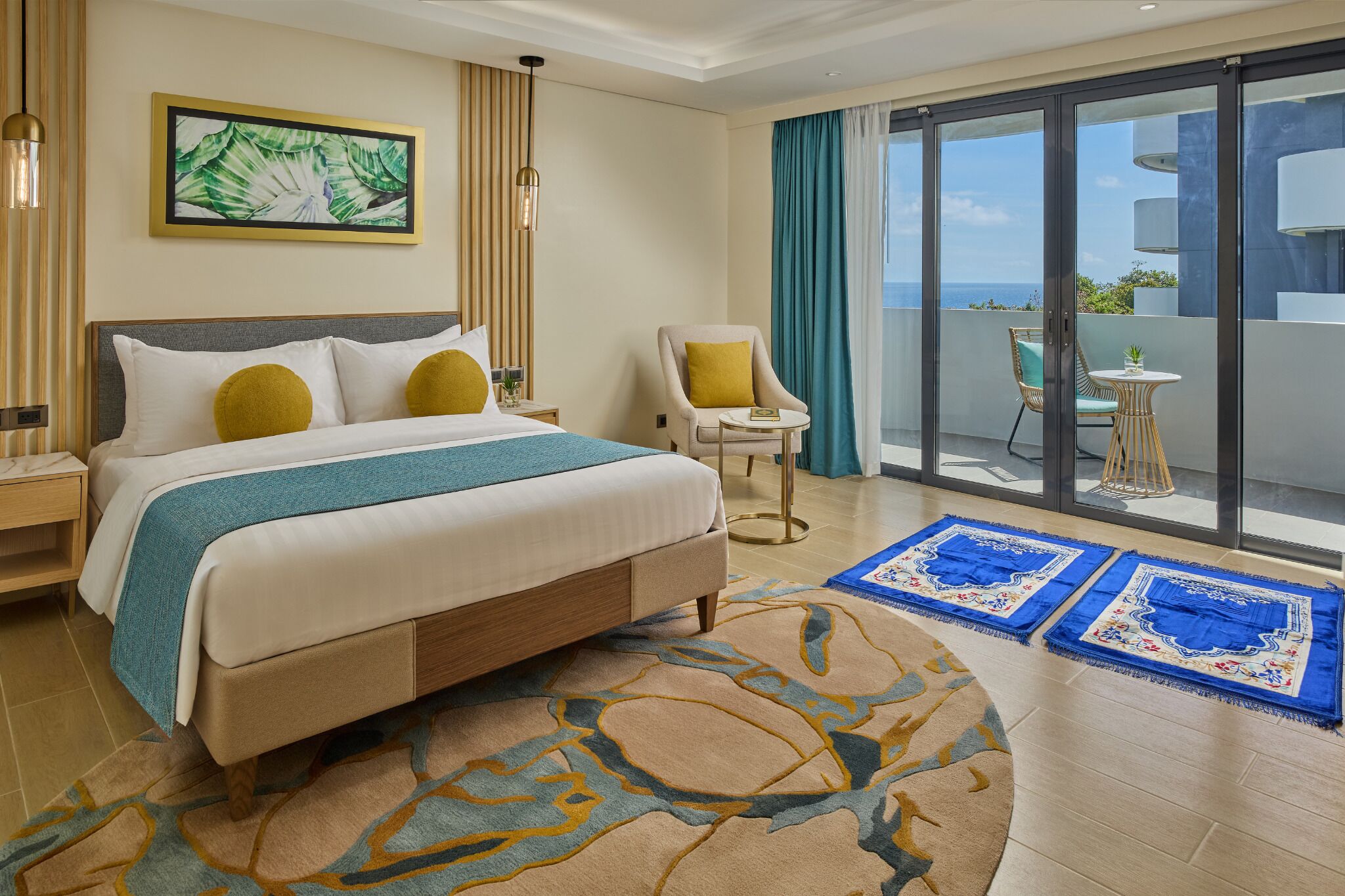 Une chambre d’hôtel avec un lit, une chaise, une petite table et une vue sur l’océan grâce à de grandes portes coulissantes.