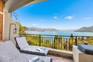 A balcony with a view of a lake and mountains, furnished with a sofa and a table. - Elegant Panorama Lake View Terrace with Pool, Stresa, Italy (Stresa)