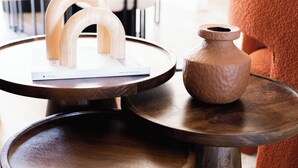 Une table ronde en bois, sur laquelle sont posés un vase et une sculpture en bois.