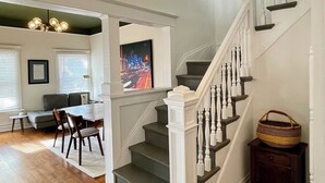 A staircase with white balusters and dark steps, leading to a landing with a basket. - Historic Downtown Raleigh 3-bedroom Home Close to Everything (Raleigh)