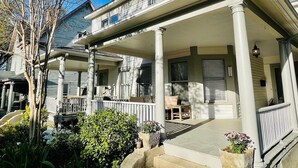 A two-story house with a covered porch, columns, and a small garden area. - Historic Downtown Raleigh 3-bedroom Home Close to Everything (Raleigh)