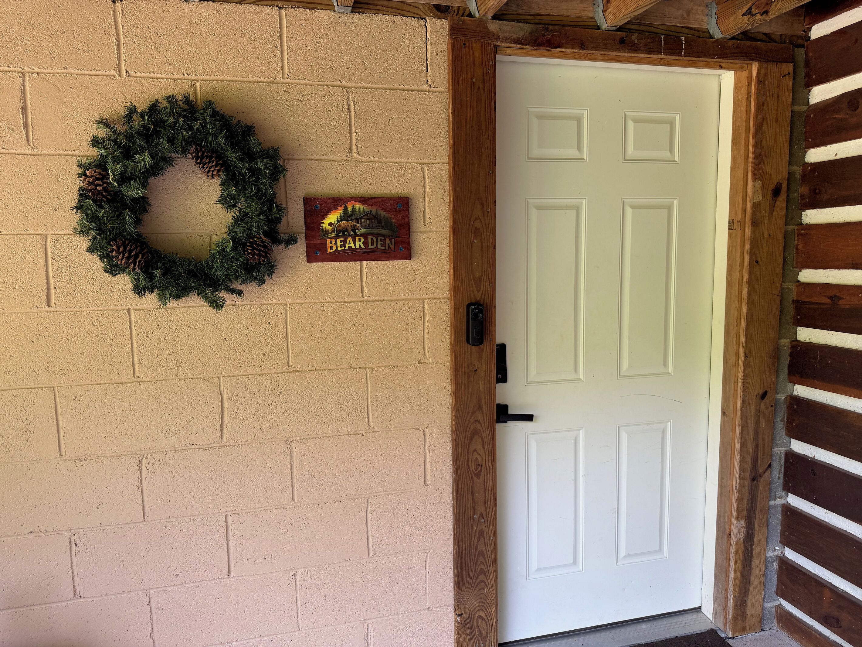 A white door with a wooden frame, a brick wall, a wooden ceiling, and a bear den sign.