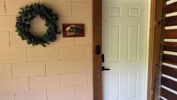 A white door with a wooden frame, a brick wall, a wooden ceiling, and a bear den sign.