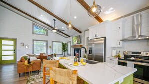 A modern kitchen with white cabinets, a stainless steel refrigerator, and a large island with bar stools.