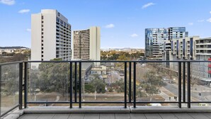 Ein Balkon mit Blick auf moderne Gebäude und einen Park.
