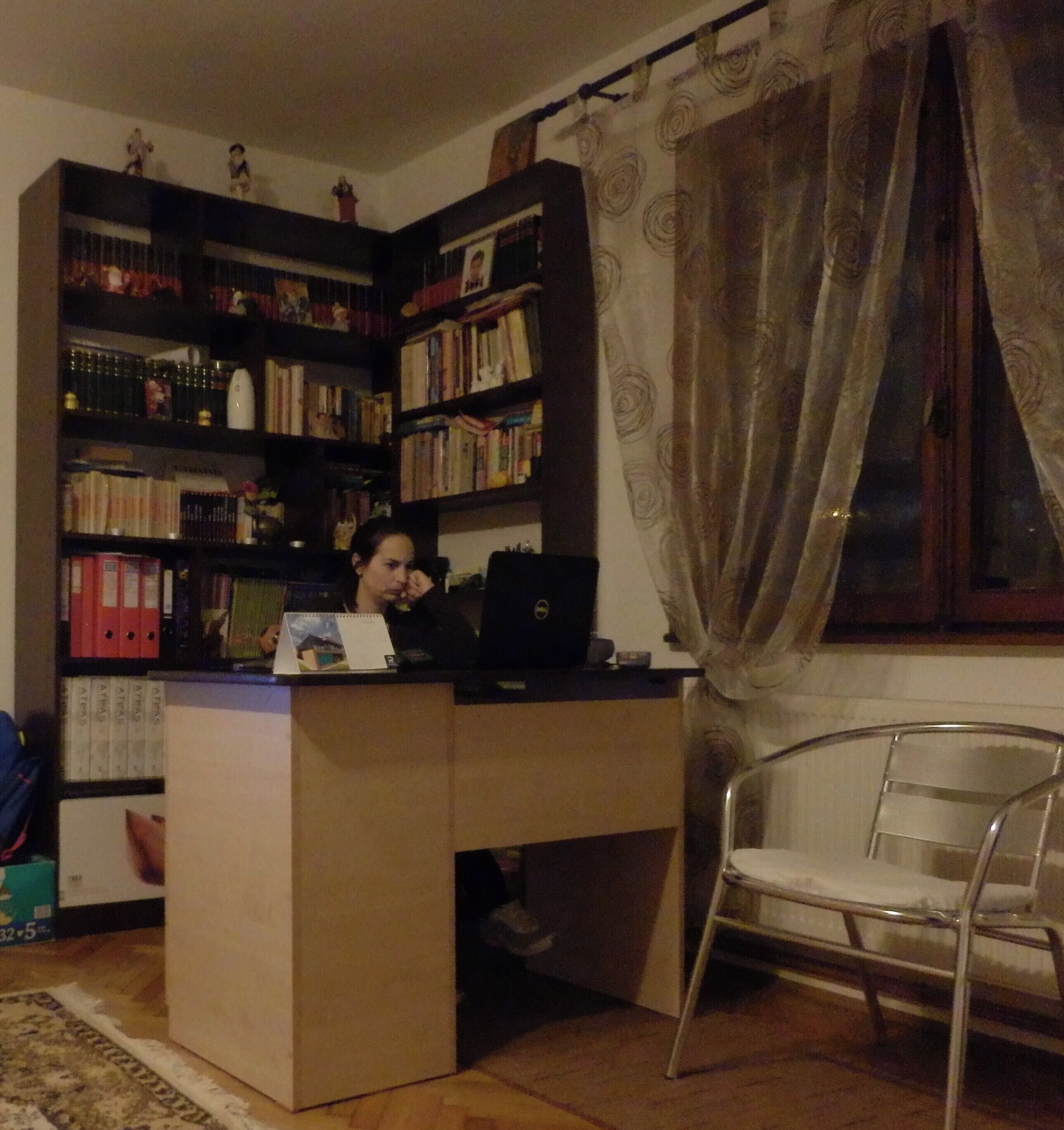 Ein Homeoffice mit Schreibtisch, Stuhl und Bücherregalen voller Bücher.