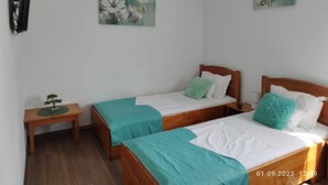 Una habitación con dos camas individuales, una mesita de madera y un aire acondicionado instalado en la pared.