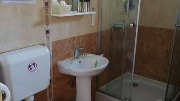 Un baño con inodoro, lavamanos y cabina de ducha de vidrio.