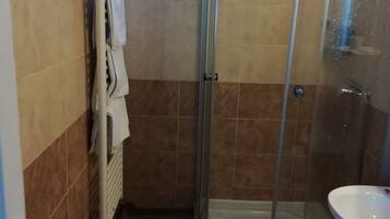 A bathroom with a glass shower enclosure, a white sink, and a towel rack.