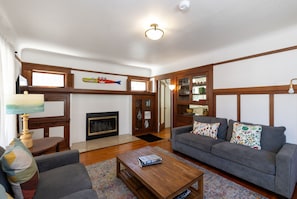 A living room with a fireplace, wooden beams, a sofa set, and a coffee table. - Capitola Village Craftsman Cottage- 4 min to beach (Capitola)