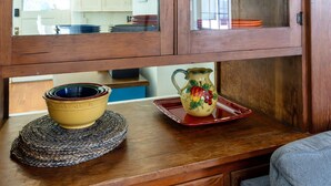 Een houten kast met glazen deuren, een geweven placemat en een keramieken pitcher.