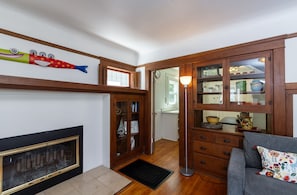 A living room with a fireplace, wooden cabinets, a sofa, and a decorative fish.