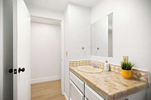 A bathroom with a white sink, a mirror, and a potted plant. - @ Marbella Lane - Modern Cabin-style 2BR Home (Campbell)