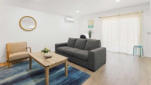 Una sala de estar con sofá, sillón, mesa de centro y una planta pequeña.