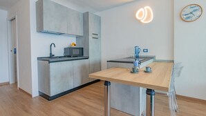 A modern kitchen with a microwave, kettle, and coffee maker on a countertop. - Sea view apartment in Porto Azzurro (Porto Azzurro)