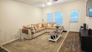 A living room with a sectional sofa, a coffee table, a rug, and a ceiling fan.