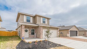 A two-story house with a brick facade, a front porch, and a garage.