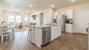 A modern kitchen with a central island, stainless steel appliances, and a dining area with a sofa and chairs.