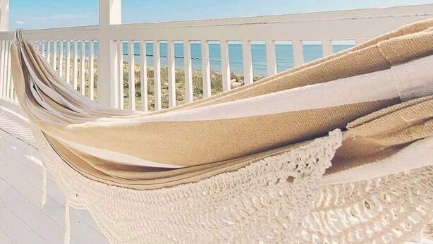 A hammock on a white porch with a view of the ocean. - Sojourn The Lighthouse  Beach Front Resort Villa (Norfolk)