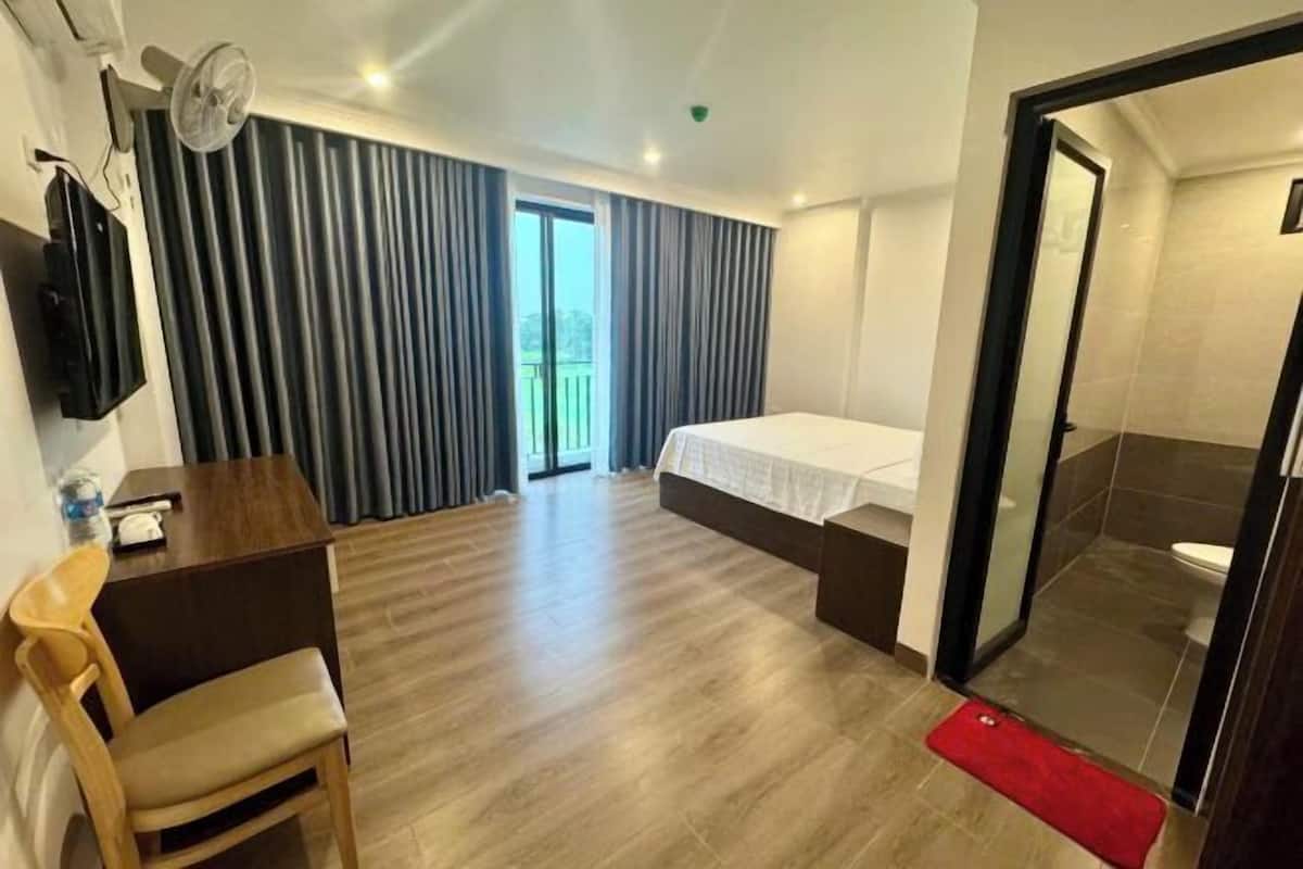 Ein Hotelzimmer mit Bett, Schreibtisch, Stuhl, Fernseher und einer Schiebetür zum Badezimmer.