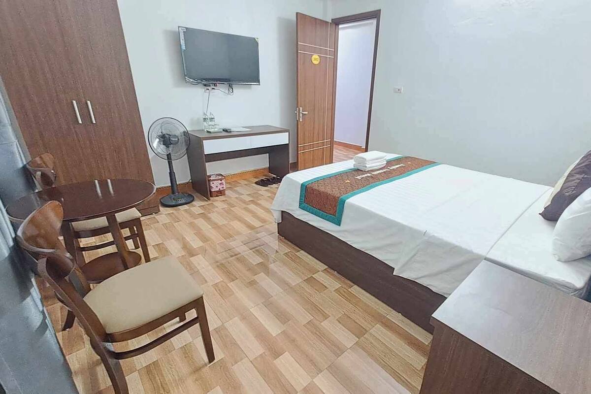 Ein Hotelzimmer mit Bett, Schreibtisch mit Stuhl, Fernseher und Kleiderschrank.