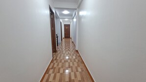 Un couloir aux murs blancs et au sol recouvert d’un parquet en bois.
