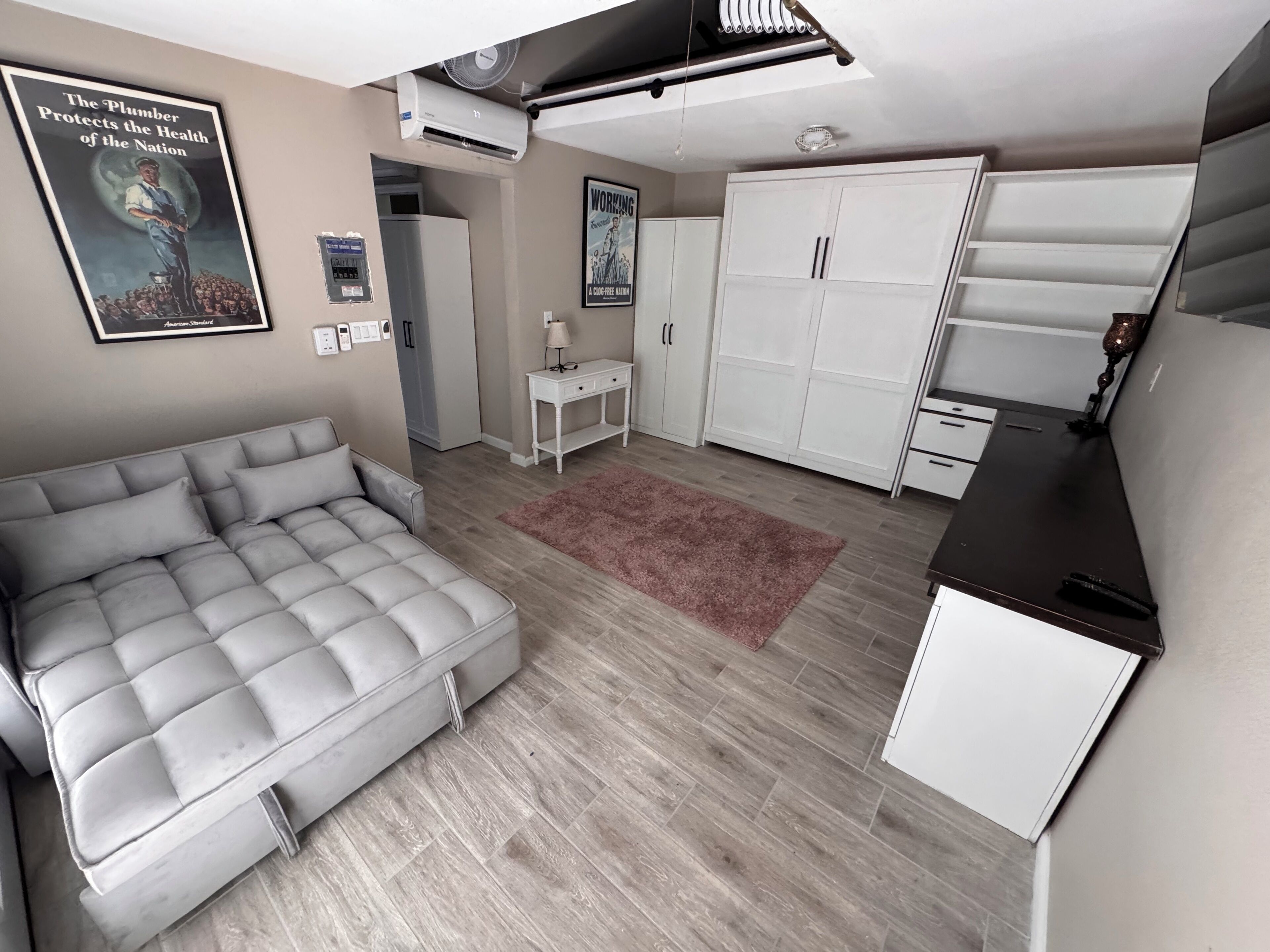 Un espace de vie compact comprenant un canapé, une armoire et un coin cuisine.